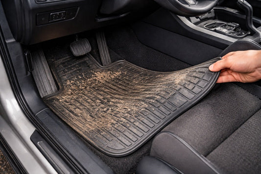 Dirty car floor mat inside vehicle with mud and debris