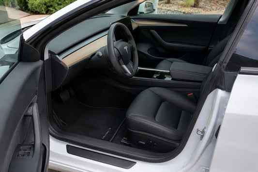 Tesla interior with standard carpet floor mats installed in the front seating area